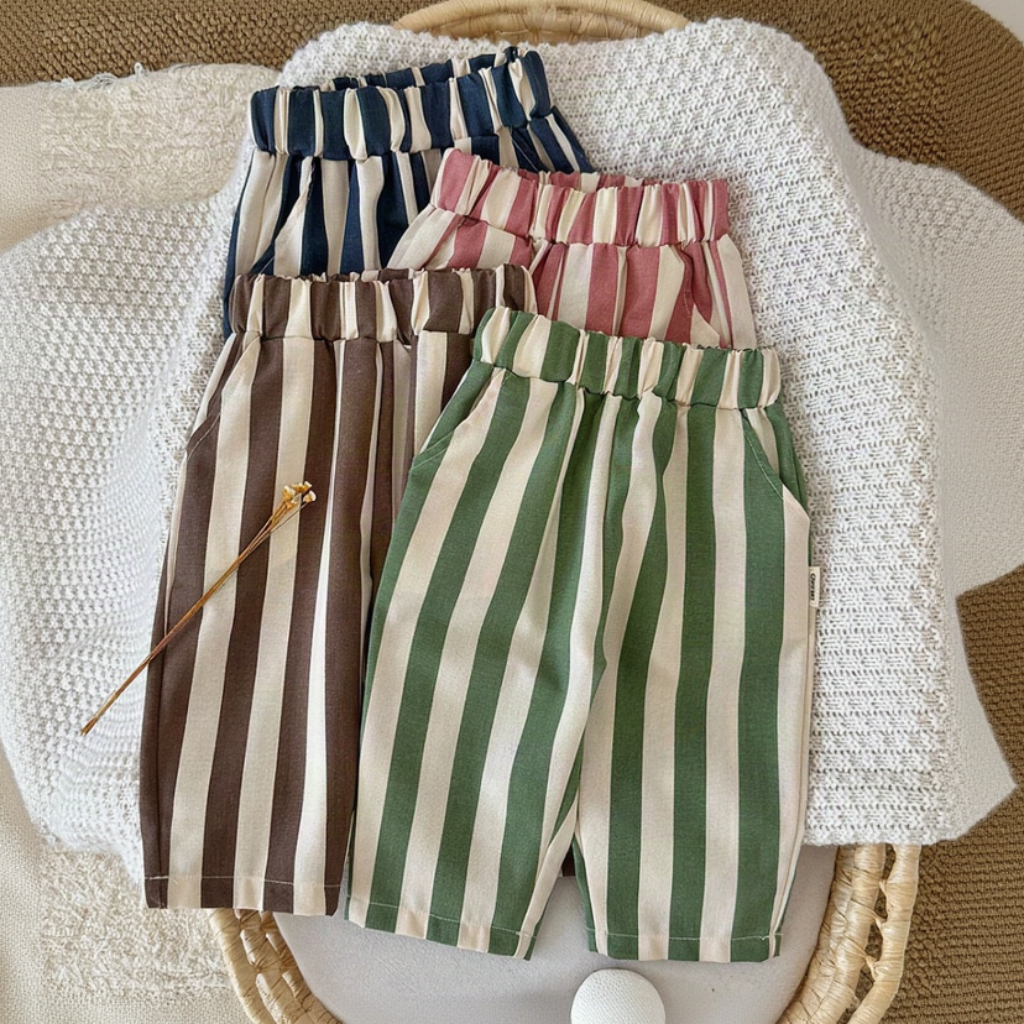 Blue, pink, brown and green striped baby pants arranged on a knit blanket