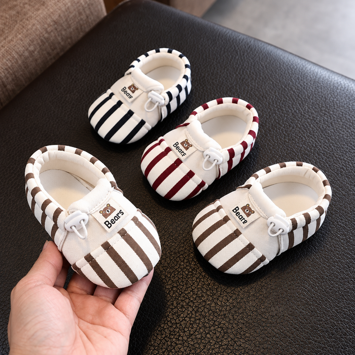 Brown, red, and black striped baby shoes, with one brown shoe held in a hand
