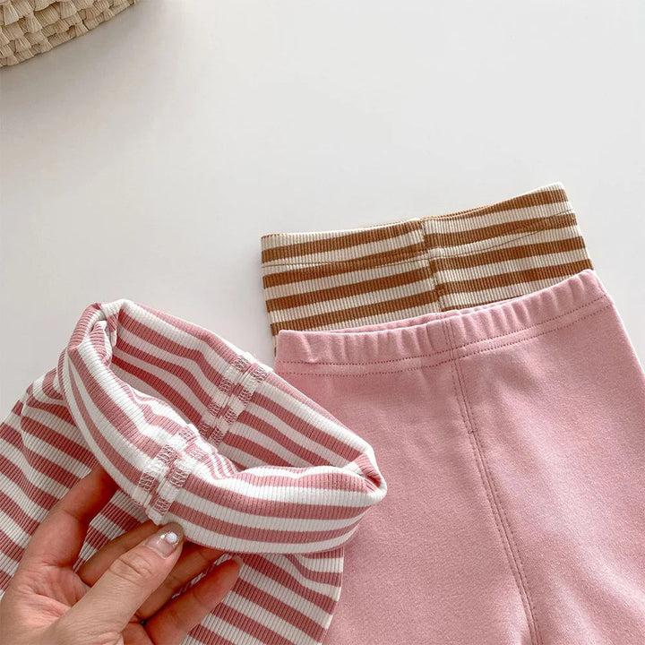 Close-up of a pink-striped elastic waistband beside solid pink and brown-striped leggings