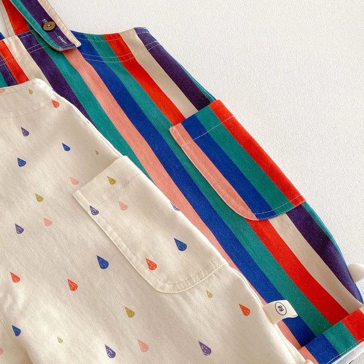 Close-up of side pockets and buttoned straps on striped and cream raindrop-print overalls