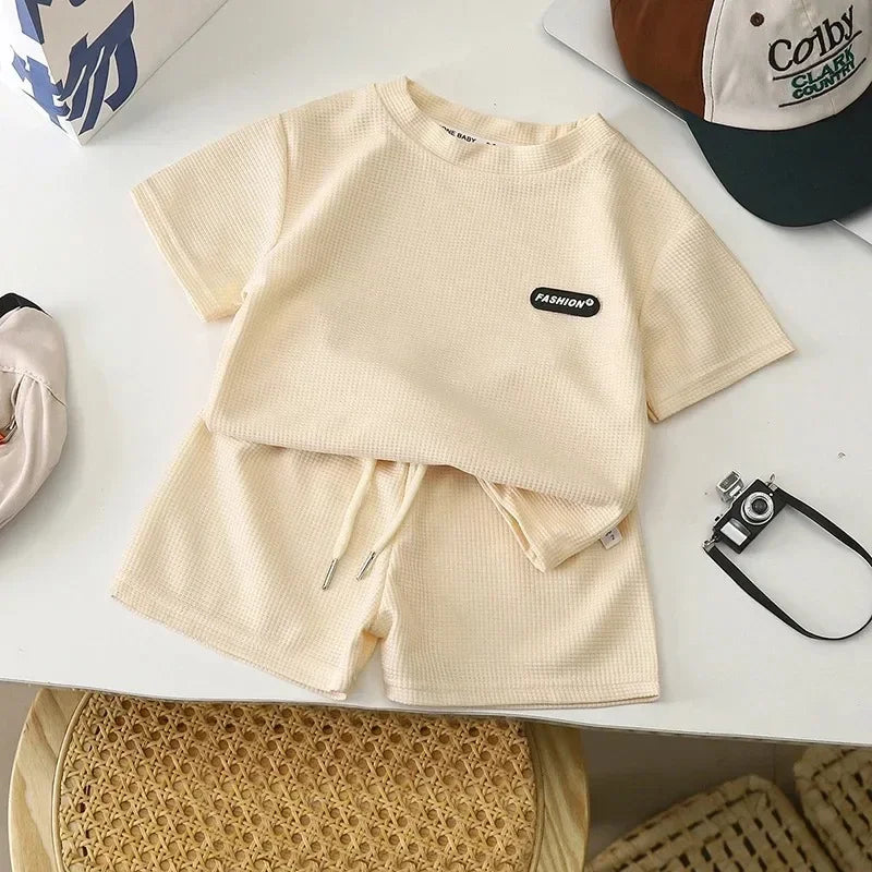 Beige short-sleeve cotton T-shirt and coordinating drawstring shorts laid flat
