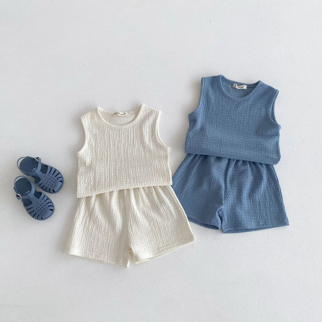 Beige and blue sleeveless cotton tops with matching shorts laid flat.