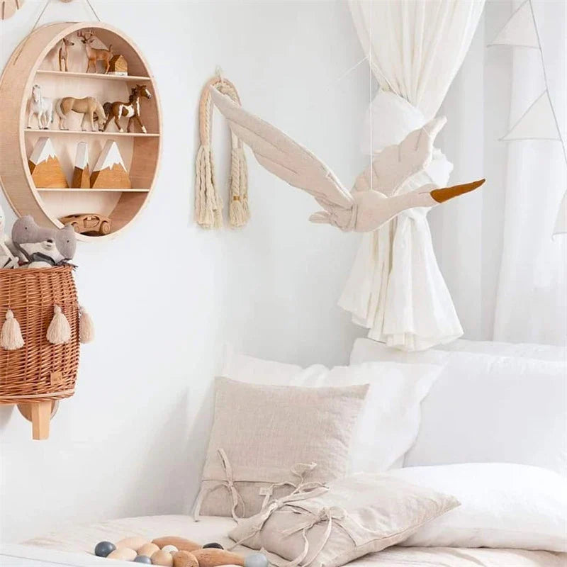 Fabric swan hanging beside sheer curtains in a light-colored nursery