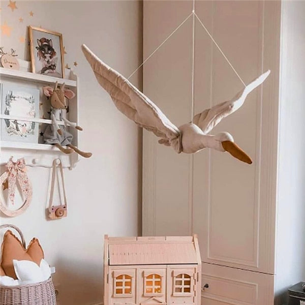 Swan decoration with a brown beak hanging beside nursery shelves and a dollhouse
