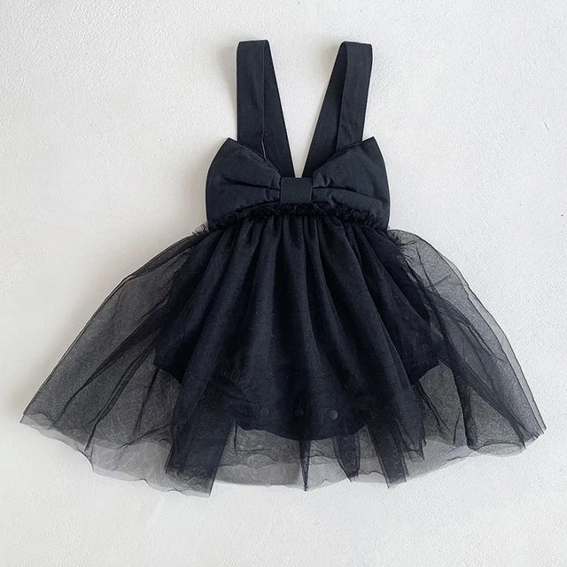 Black baby romper dress with wide shoulder straps, a bow detail and a sheer skirt overlay.