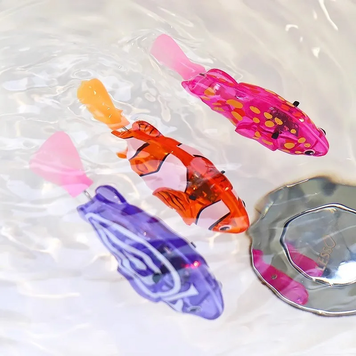 Pink, orange, and purple swimming fish toys in water beside a sink drain