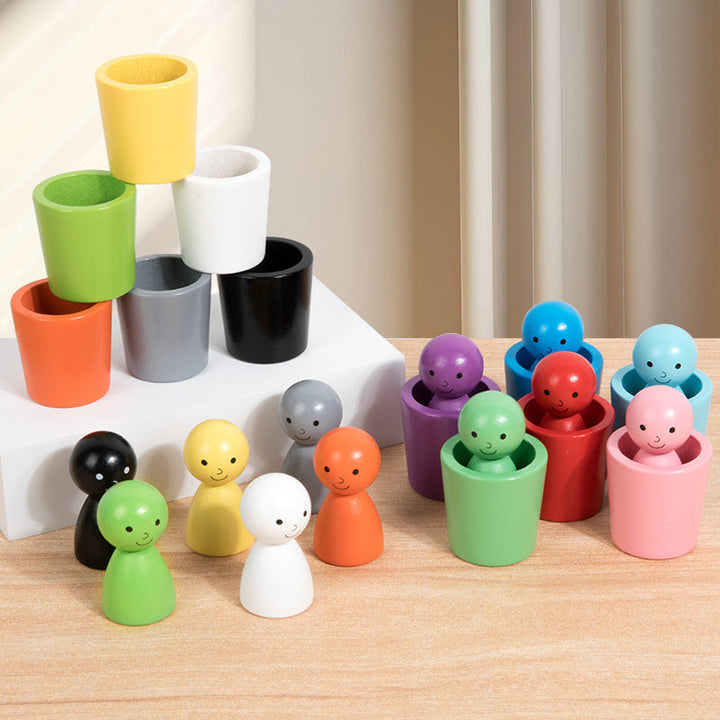 Wooden sorting figures beside matching cups and a six-cup tower on a tabletop