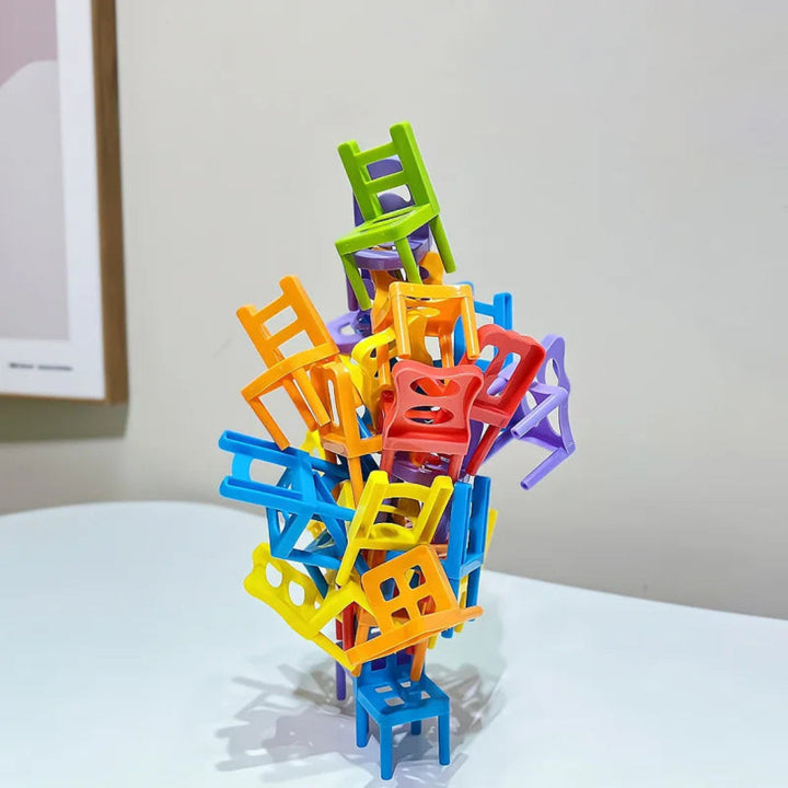 A tall tower of multicolored miniature chairs balanced on a tabletop