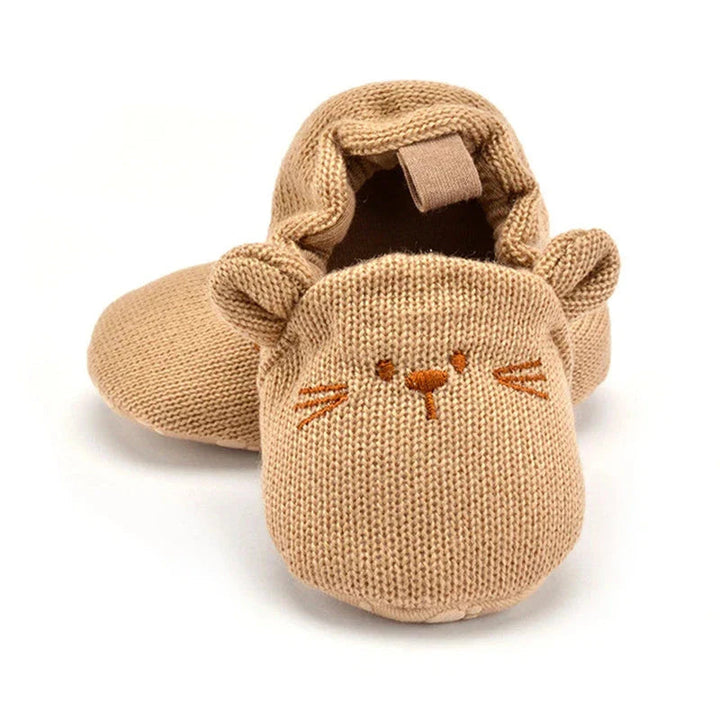 Tan knit baby slippers with embroidered animal faces and small ears, shown from the front