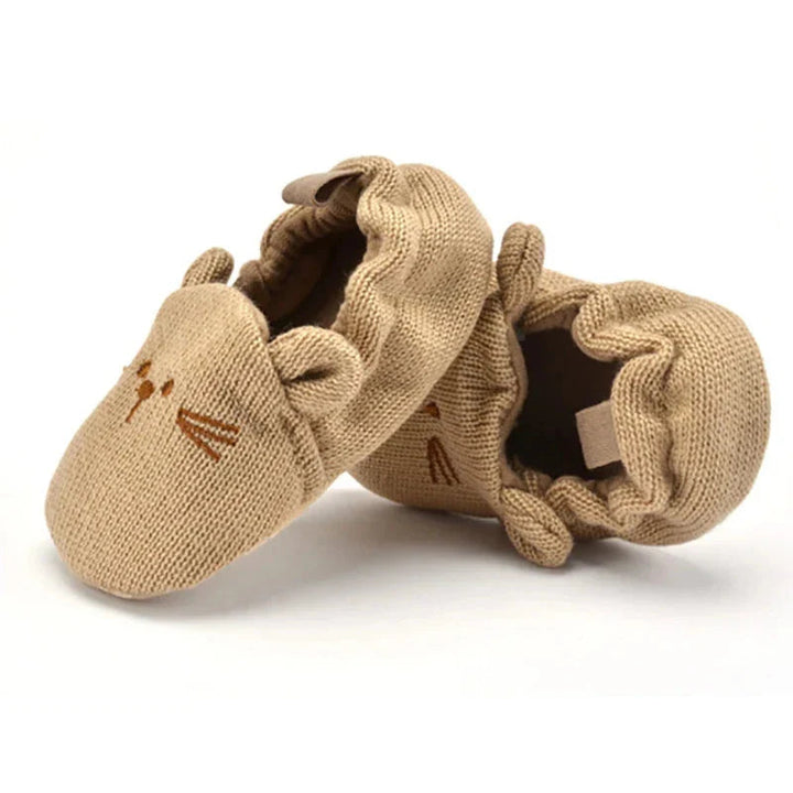 Tan knit baby slippers showing gathered heel openings and pull loops