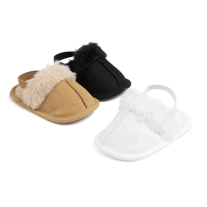 Tan, black and white plush-trimmed baby slippers on a white background
