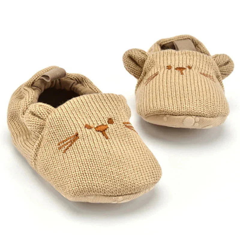 Tan animal-face baby slippers showing the knit uppers and rounded toes