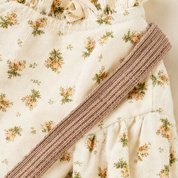 Textured taupe suspender strap over the floral long-sleeve blouse