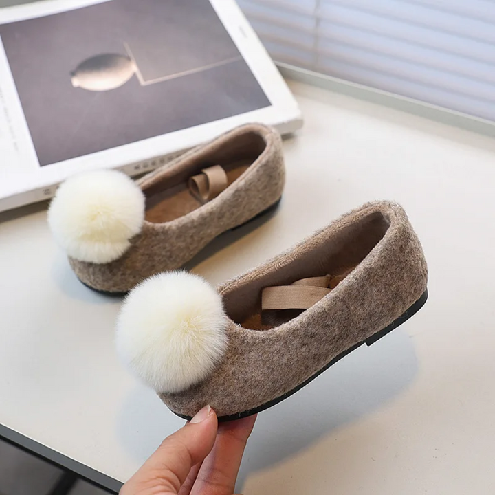 Taupe pom-pom ballet flats showing rounded toes and low black outsoles