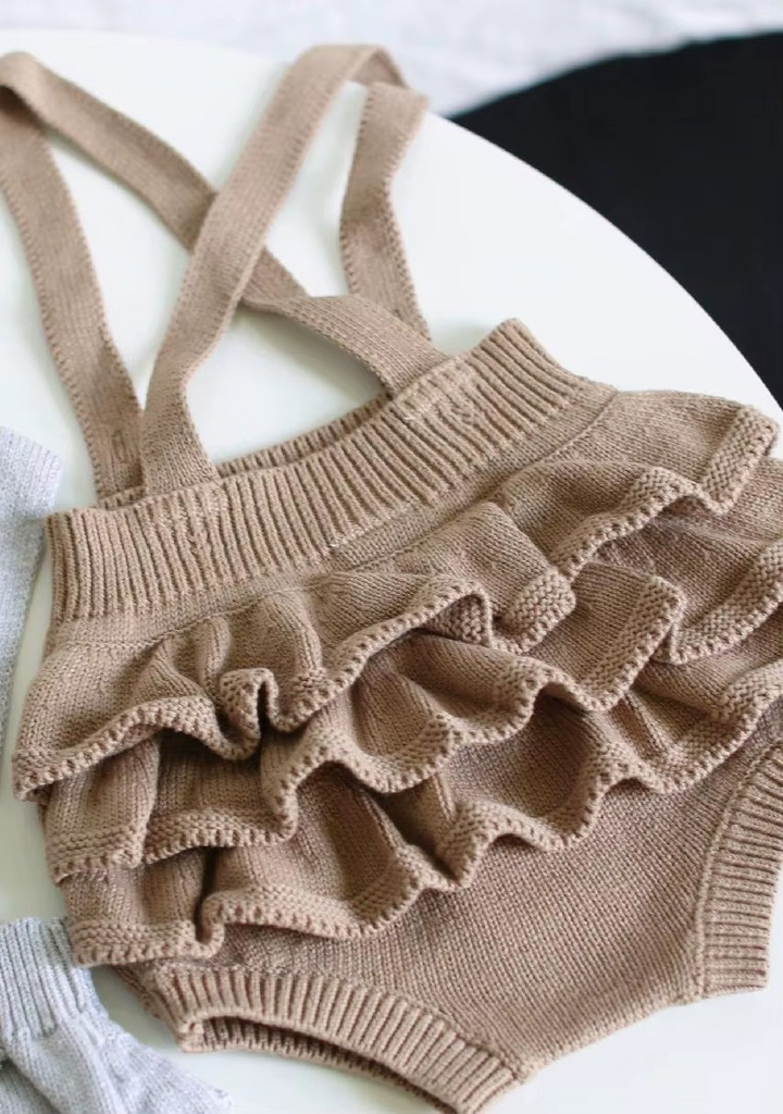 Taupe knit romper viewed from the back with three rows of ruffles
