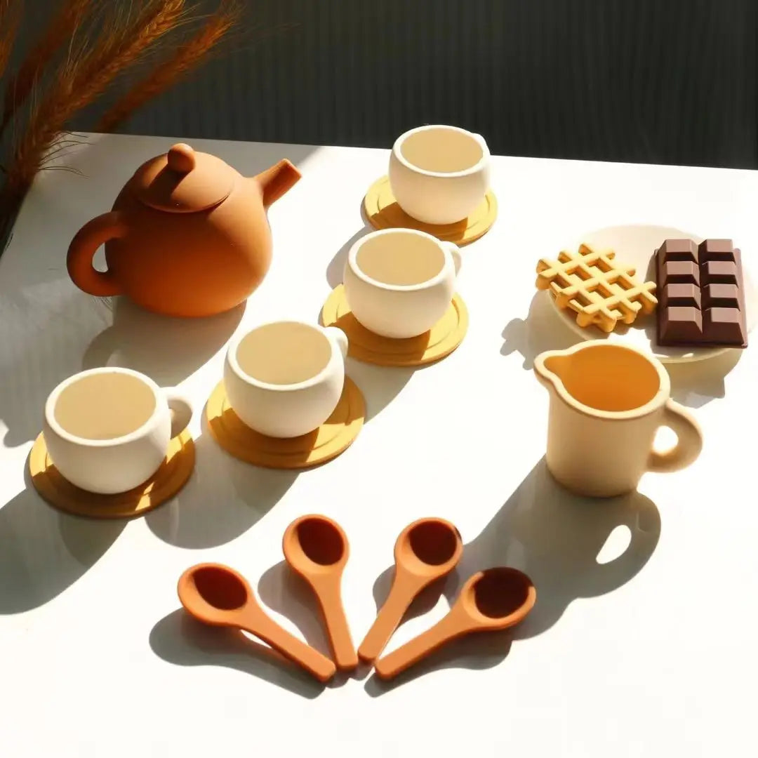 Tea party play pieces arranged with a teapot, four cups and saucers, spoons, and a pitcher