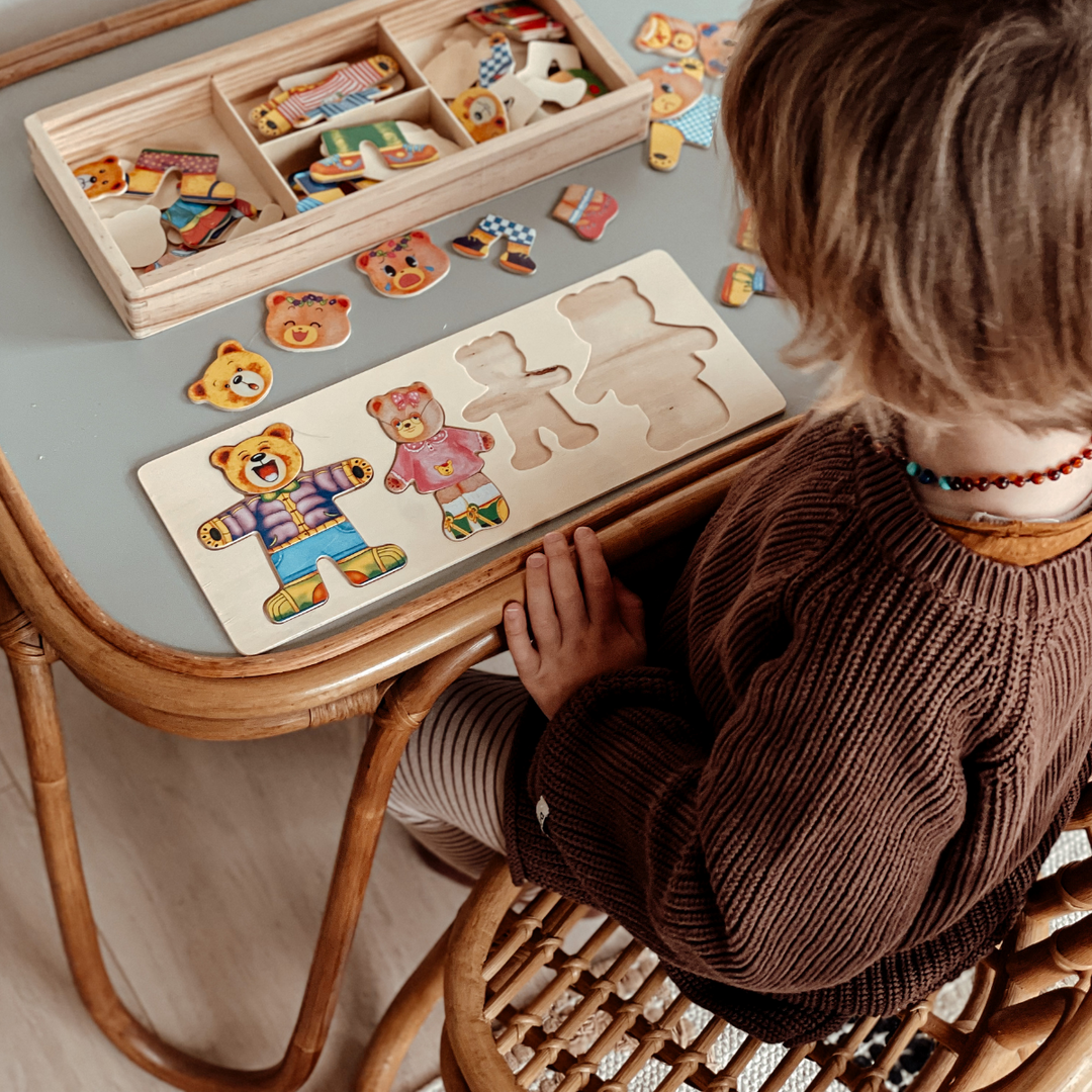 Child matching heads and outfits on a four-bear wooden puzzle board