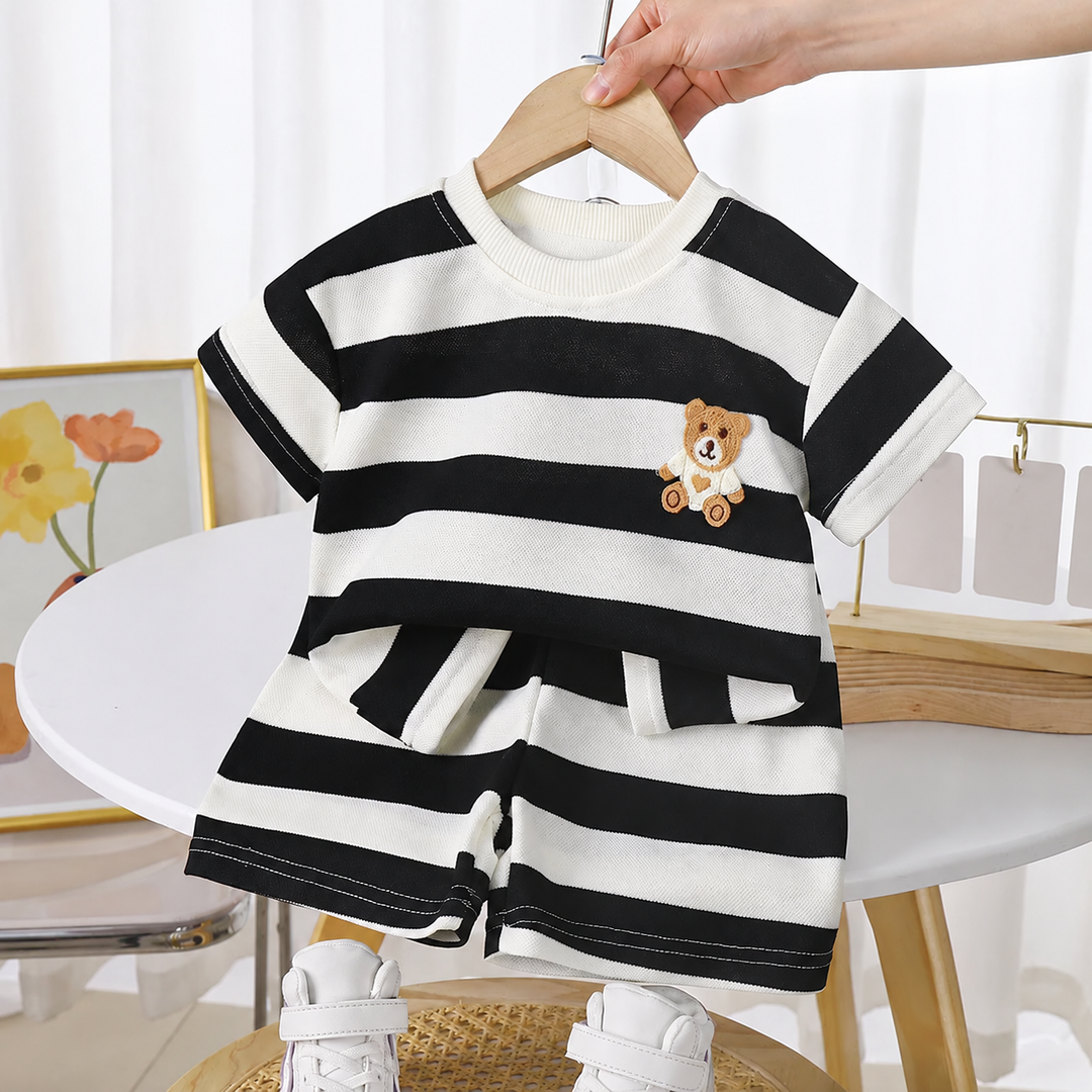 Black-and-cream striped T-shirt and shorts set on a hanger, with a teddy bear detail on the chest