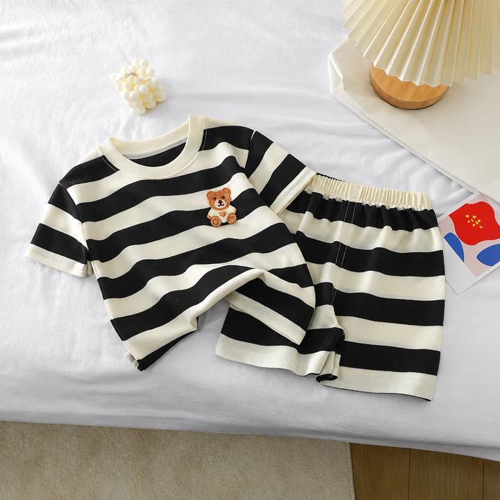 Teddy bear T-shirt and matching striped shorts laid out together on bedding
