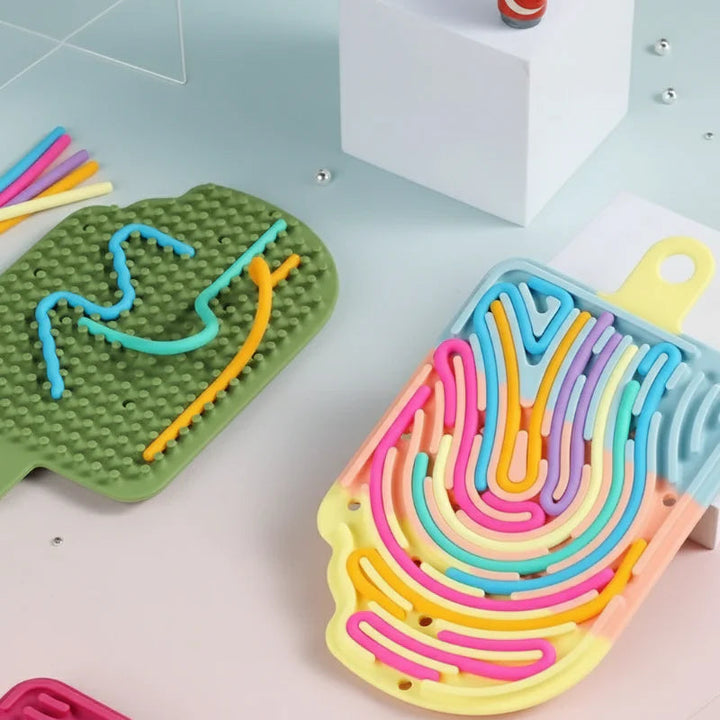 Green cloud board with a bumpy back beside a multicolor popsicle maze filled with flexible cords.