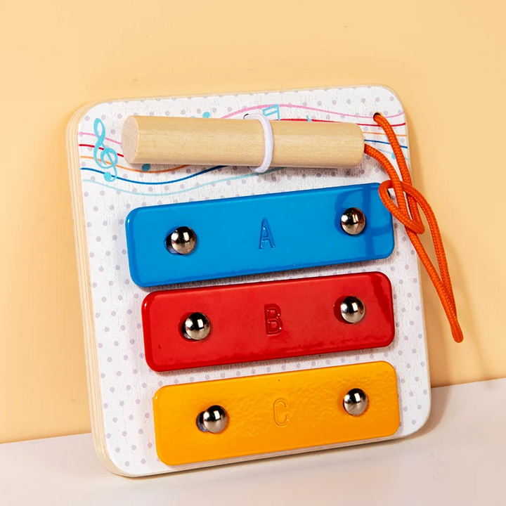 Wooden tap piano busy board with three colored bars and a tethered wooden mallet.
