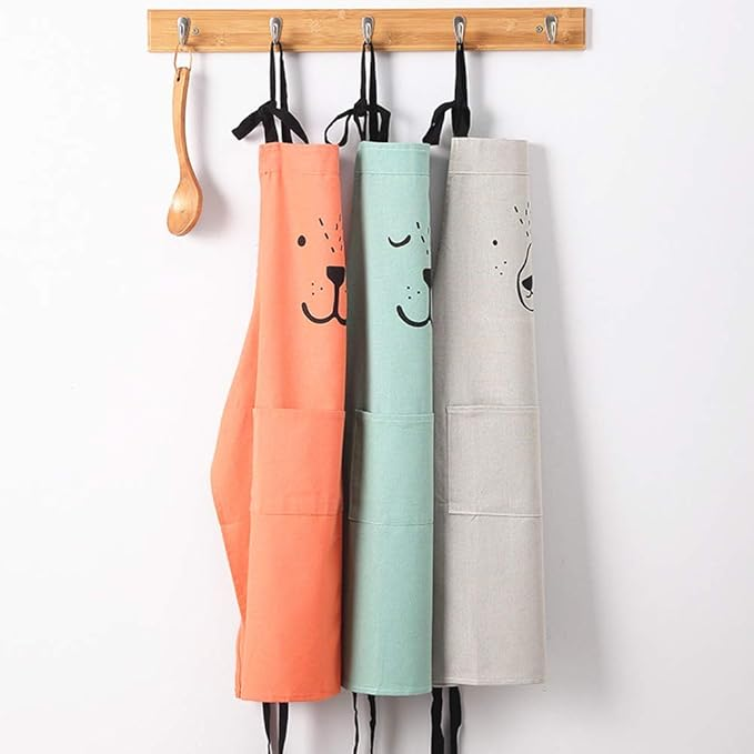 Red, green, and gray bear aprons with front pockets hanging on hooks
