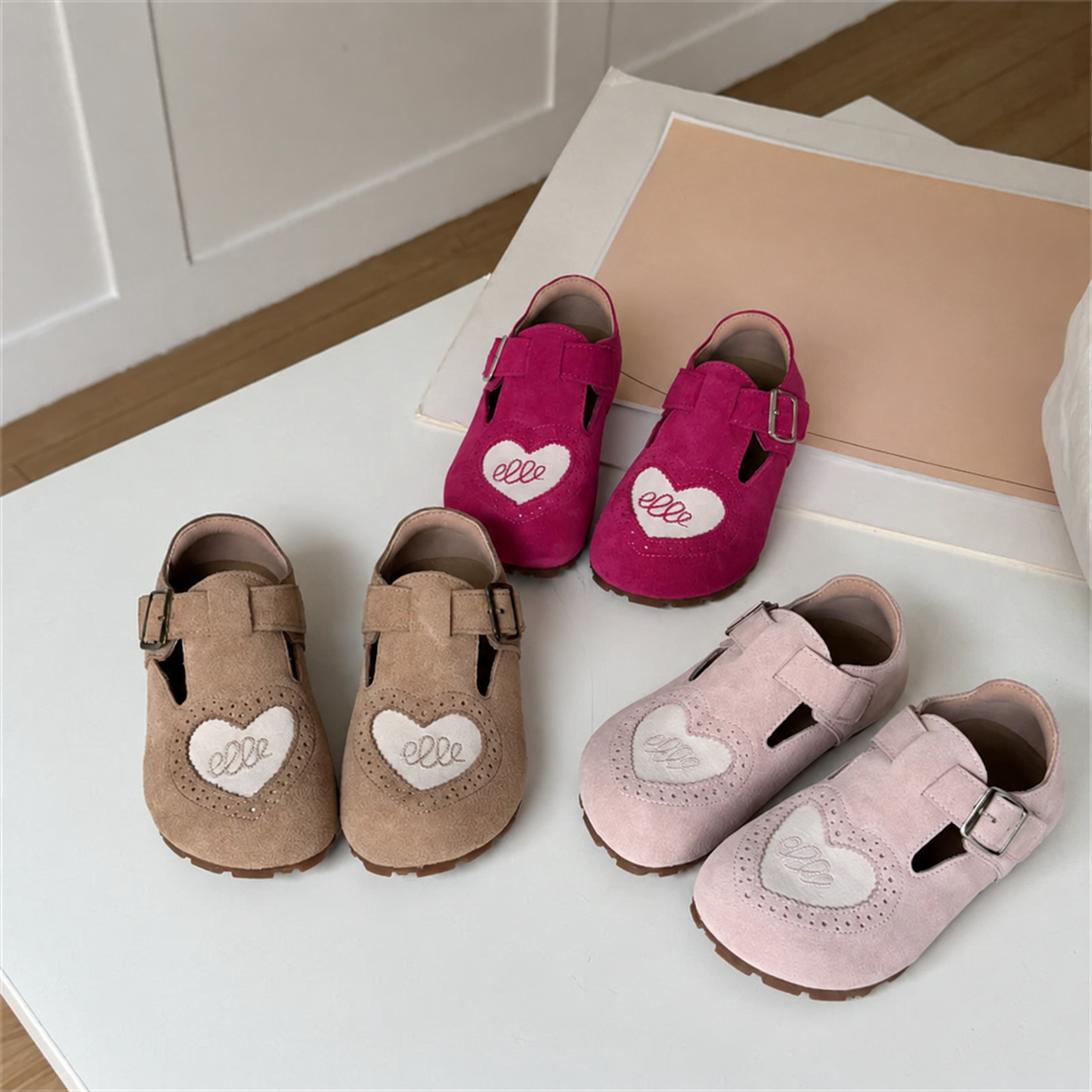 Brown, pink, and red heart-detail shoe pairs arranged on a white bench