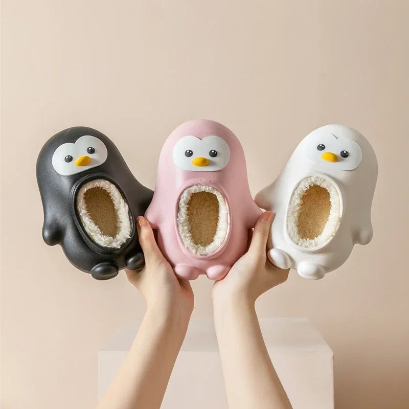 Black, pink, and white penguin slippers held up to show their faces and lined openings