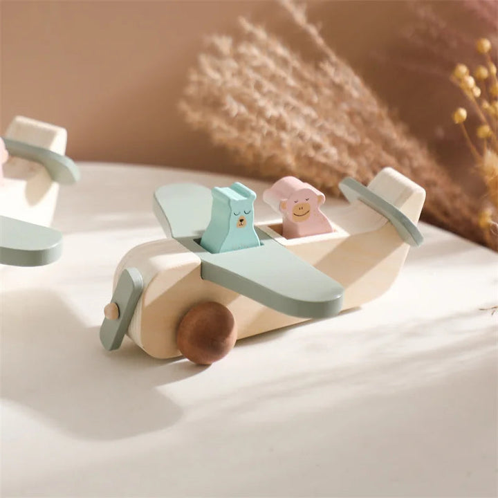 Wooden airplane with animal passengers resting on a sunlit surface