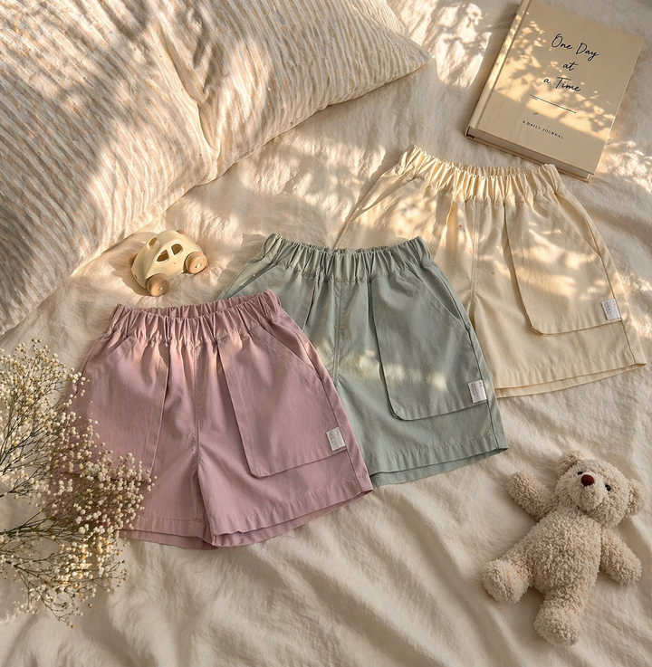 Pink, sage green, and light beige shorts arranged together on bedding.