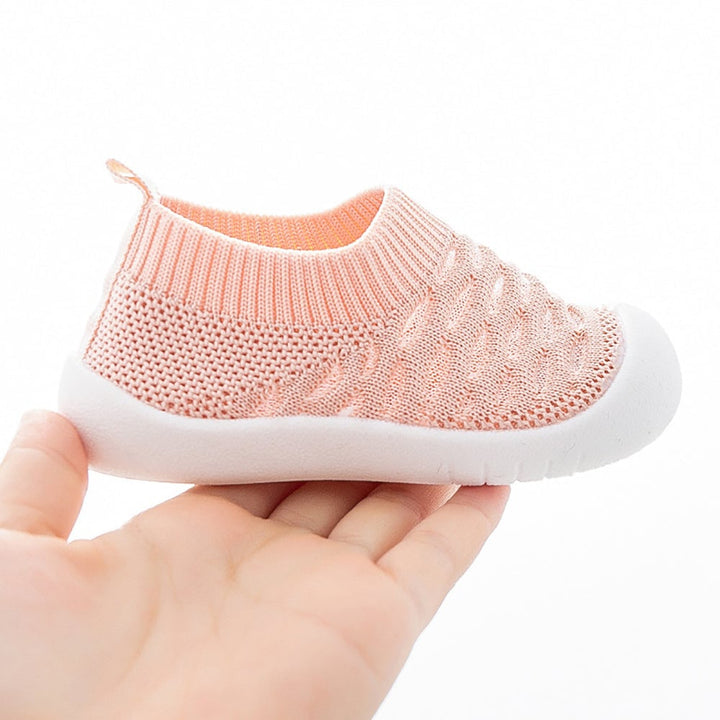 Side view of a pink knit slip-on shoe with a white sole and heel pull tab