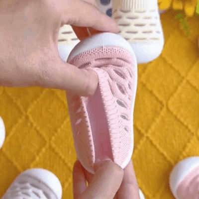 Hands bending a pink knit shoe to demonstrate its flexible sole