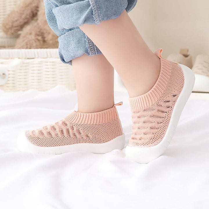 Pink slip-on knit shoes worn with rolled-up jeans
