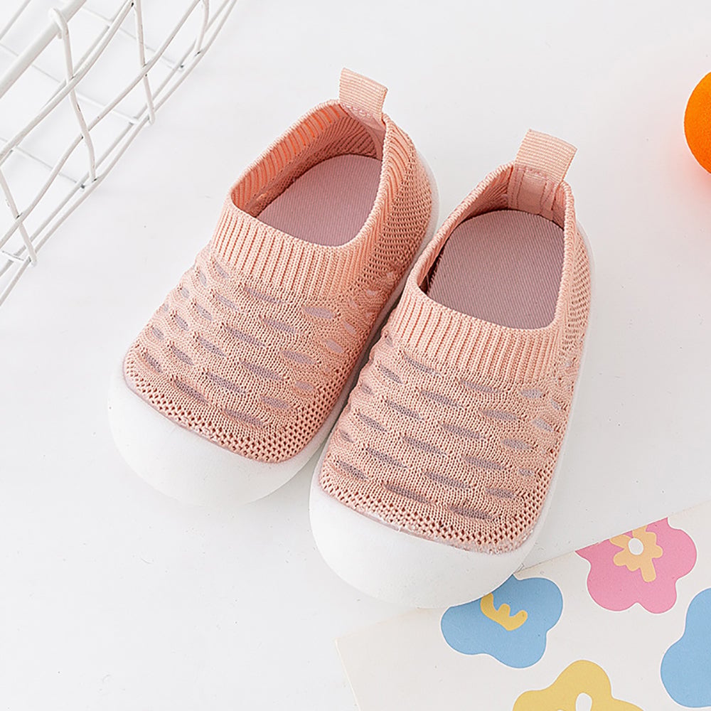Pair of pink knit slip-on shoes with ribbed openings and white soles