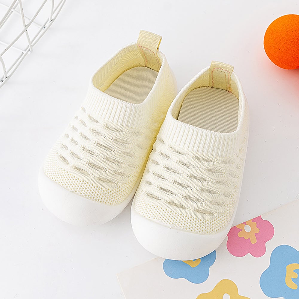 Pair of pale yellow knit slip-on shoes with heel pull tabs