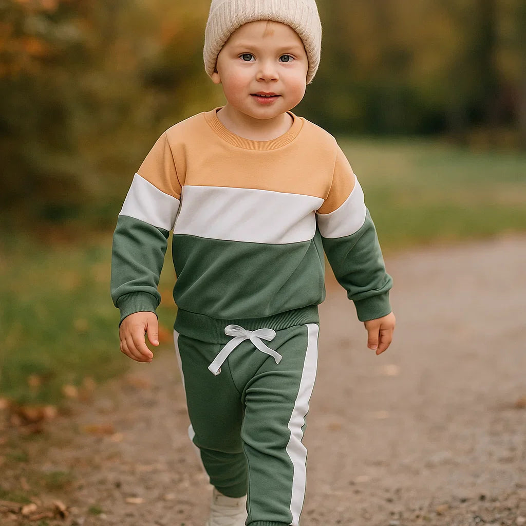 Toddler wearing a tan, white and green color-block sweatshirt with matching green joggers outdoors