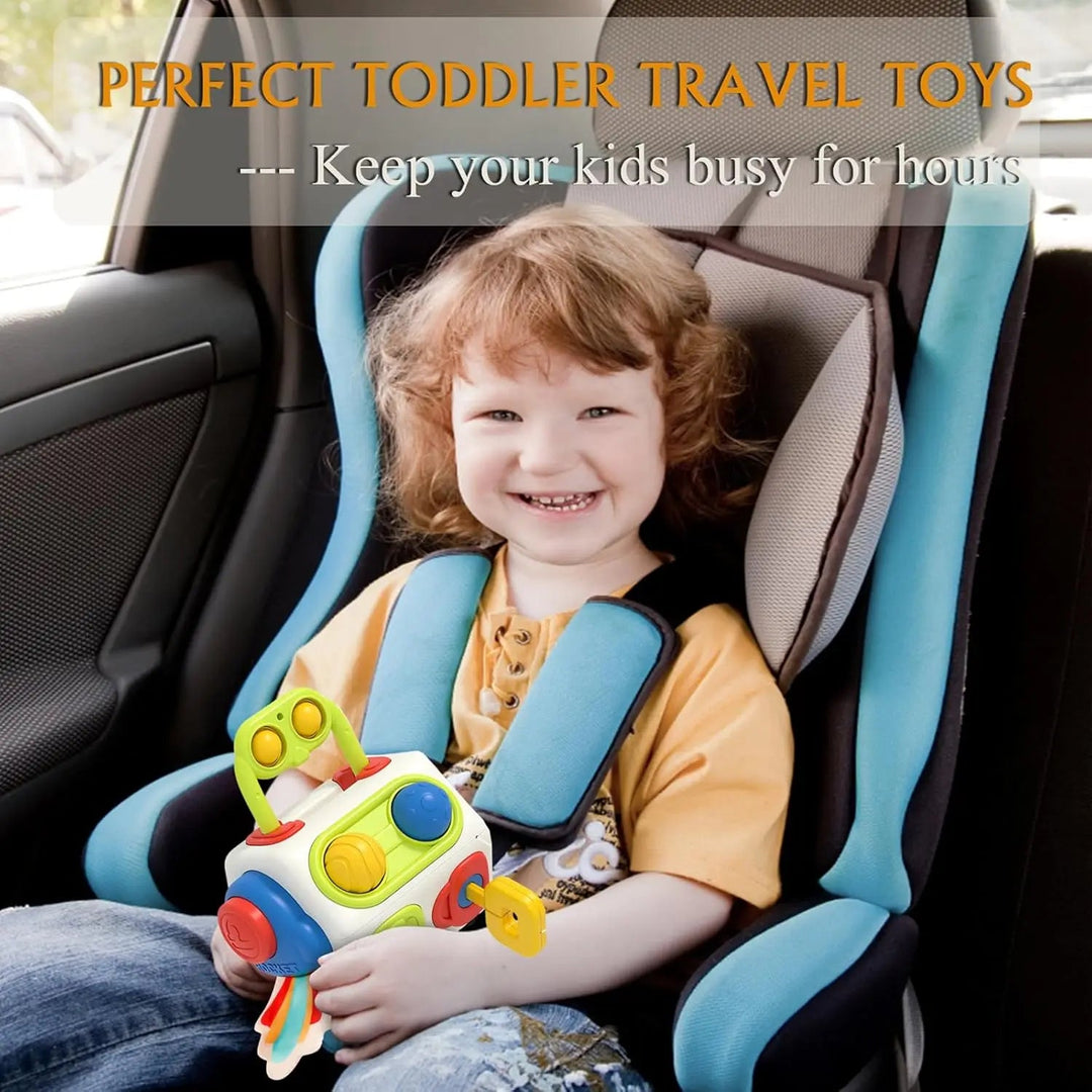 Child holding the activity cube while seated in a car seat