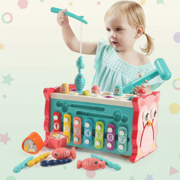 Toddler lifting a magnetic fish with the fishing rod beside the owl activity center
