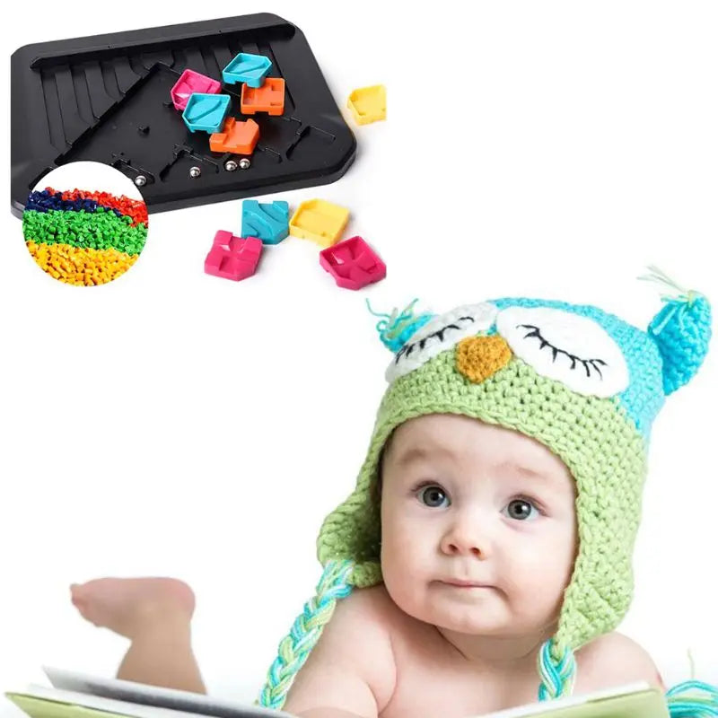 Puzzle board and loose track pieces above a baby wearing an owl hat