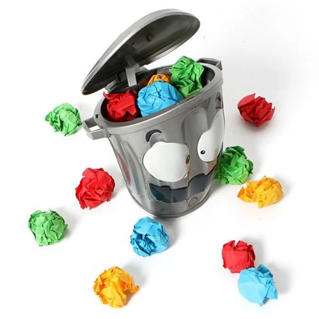 Open-lid trash can target holding colorful paper balls, with more balls arranged around it.