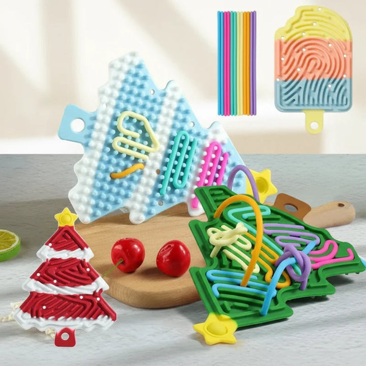 Tree-shaped silicone busy boards showing grooved and textured sides, with colorful cords and a popsicle design.