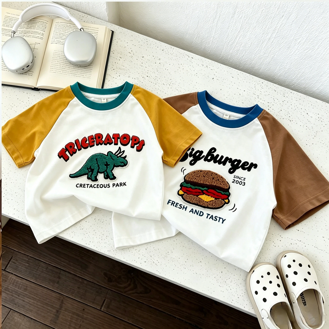 Triceratops and burger graphic T-shirts laid out with shorts and casual accessories