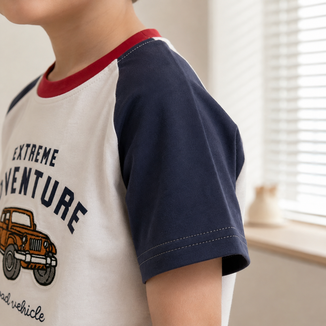 Child wearing the truck graphic T-shirt, showing its navy short raglan sleeve and red neckline