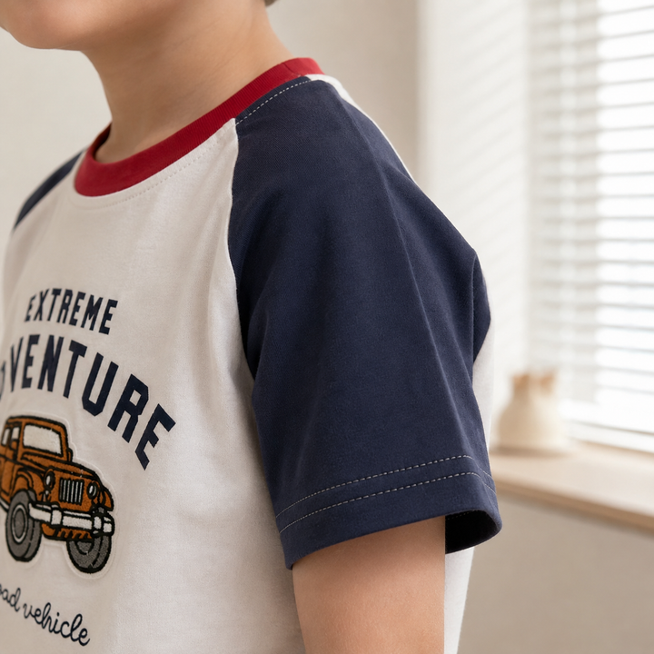 Child wearing the truck graphic T-shirt, showing its navy short raglan sleeve and red neckline