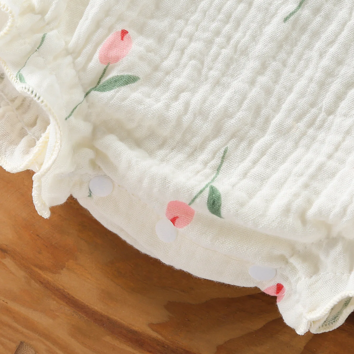 Pink tulip print and ruffled leg edge on a white cotton baby bodysuit