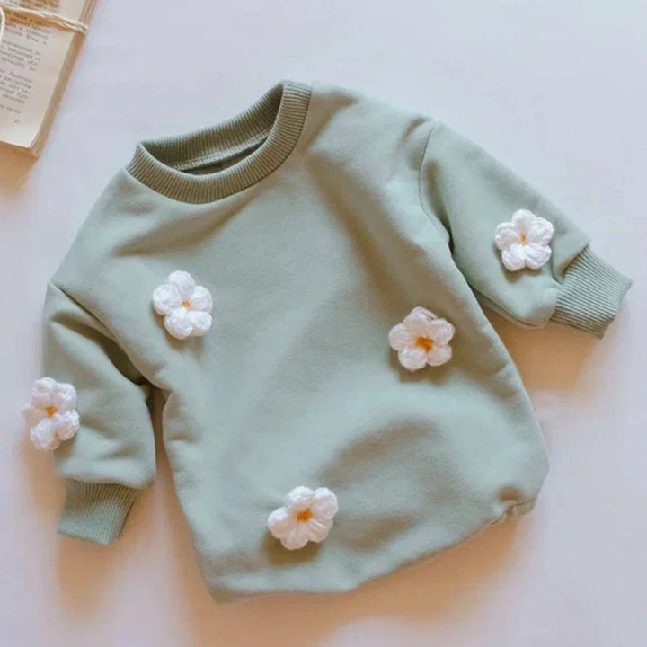 Green-toned baby romper with raised white flower details and ribbed cuffs.