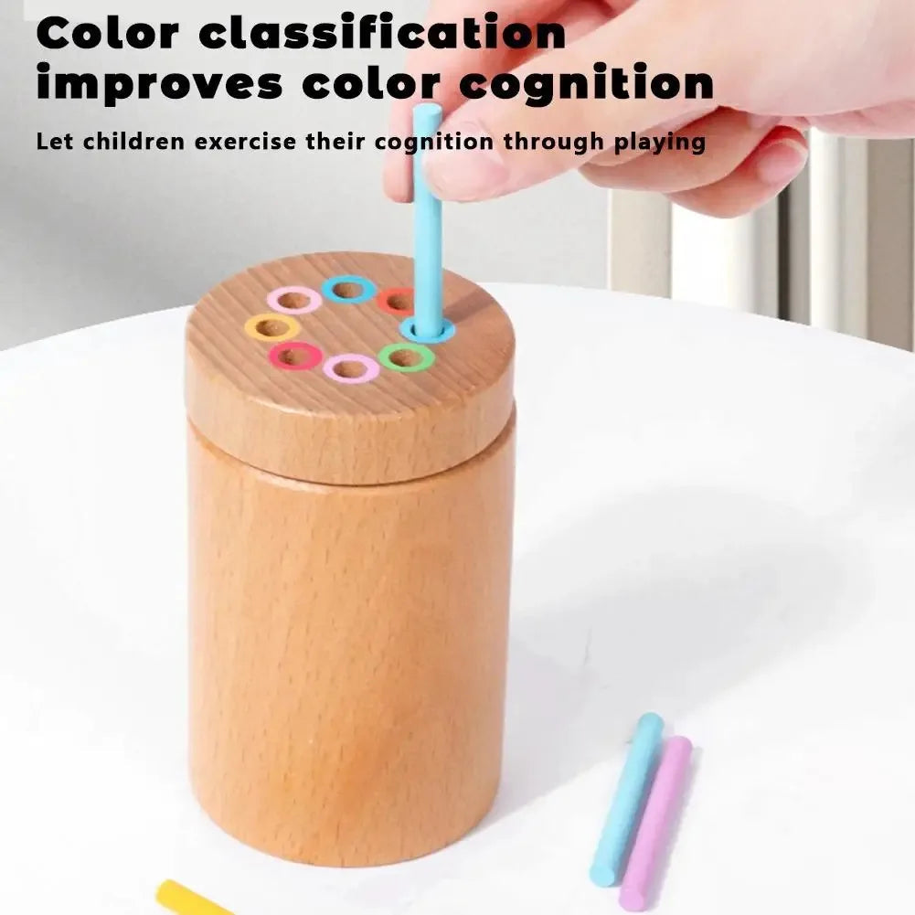 Hand guiding a turquoise stick into the matching ring on a wooden color sorting cylinder.
