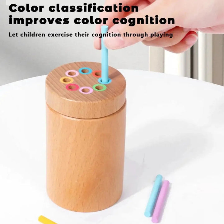 Hand guiding a turquoise stick into the matching ring on a wooden color sorting cylinder.