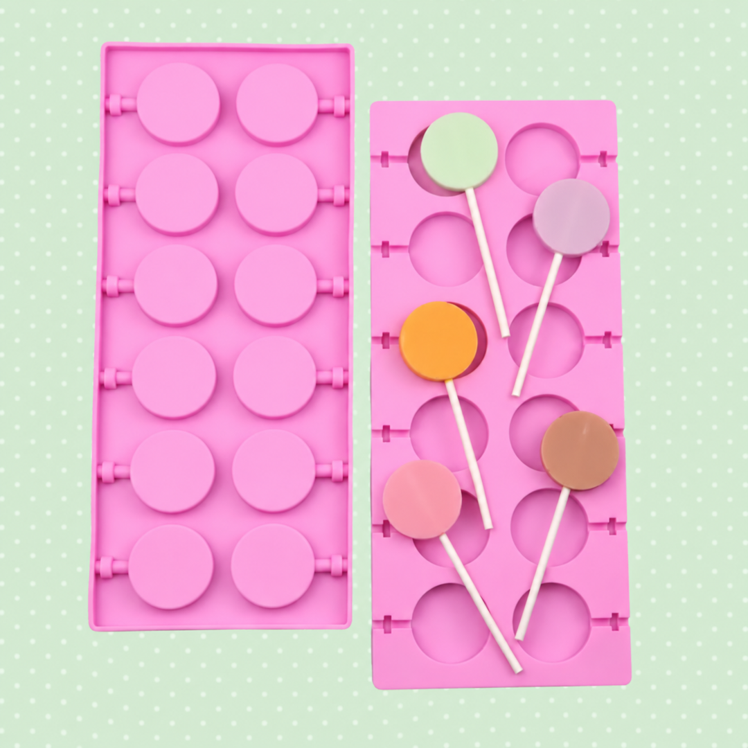 Two pink twelve-cavity round molds with colorful round lollipops on a green background