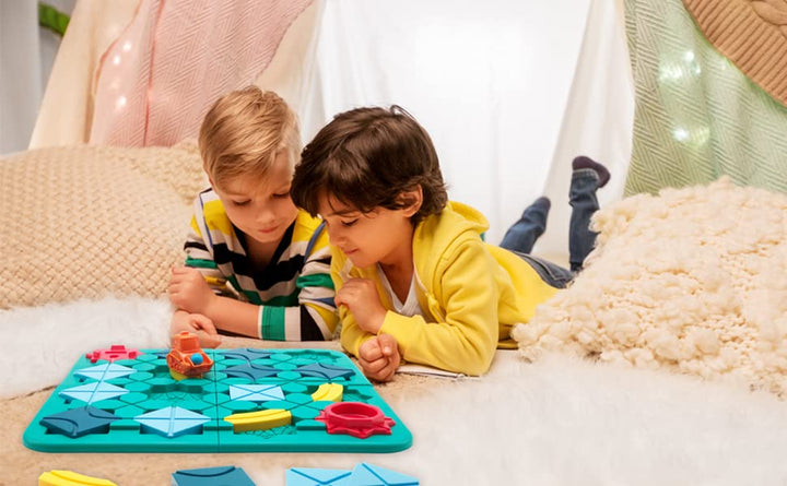 Two children lying on a rug and playing with the colorful road-building board